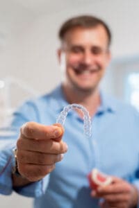 Smiling dental patient holding Invisalign clear aligners